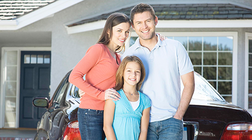 Smiling family of three at the front of their house and vehicle - Free Insurance Quotes